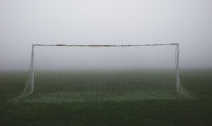 A goal and football pitch stand empty in very foggy weather.